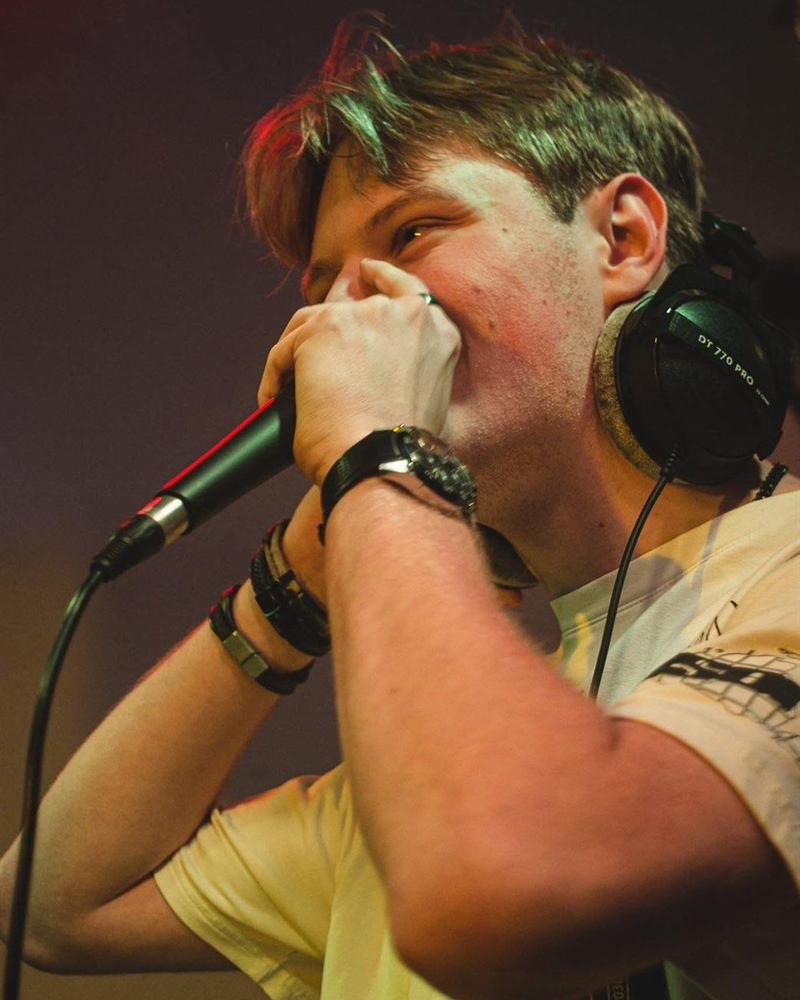 DJ met microfoon in de hand achter de draaitafels